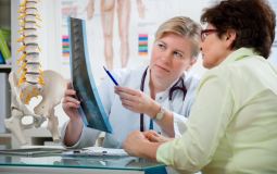 Woman and doctor examine an X-ray of a spine.