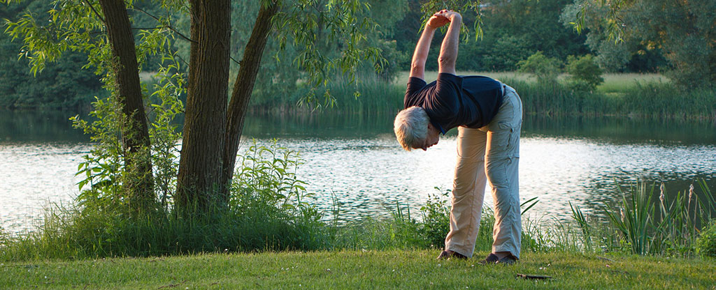 Man stretching by body of water
