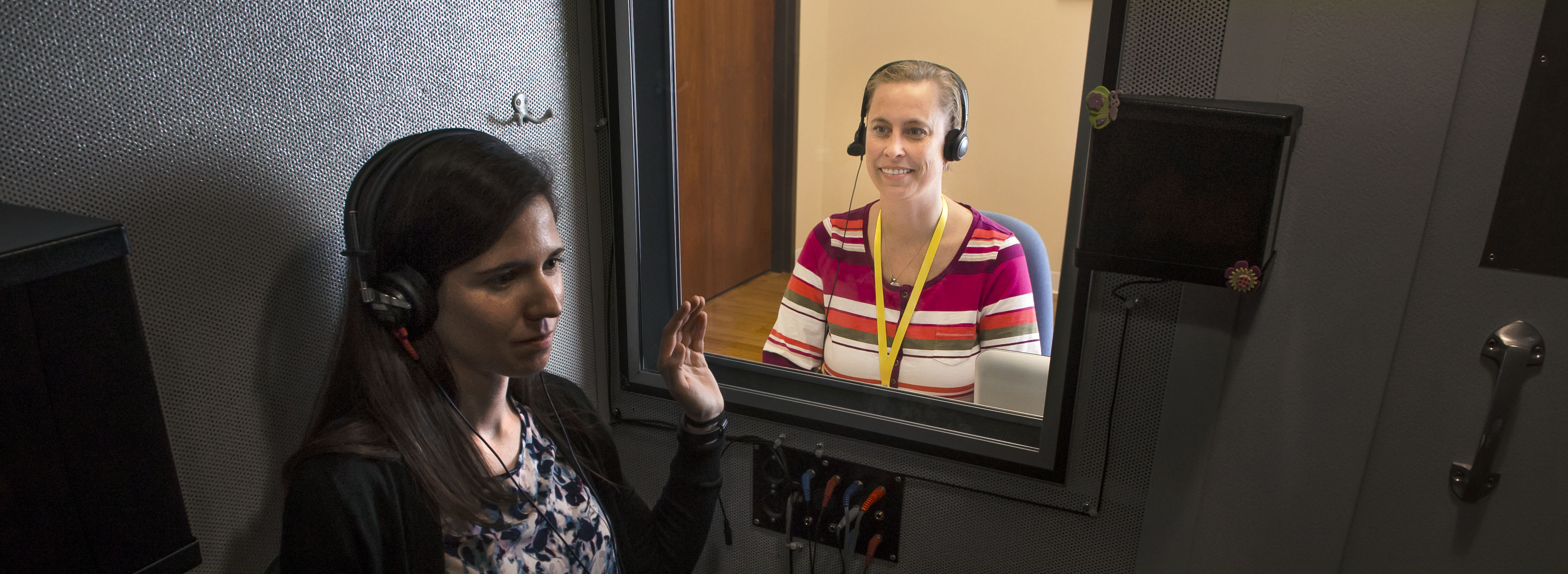 Laura Burger performs a hearing test on a patient in a soundproof booth