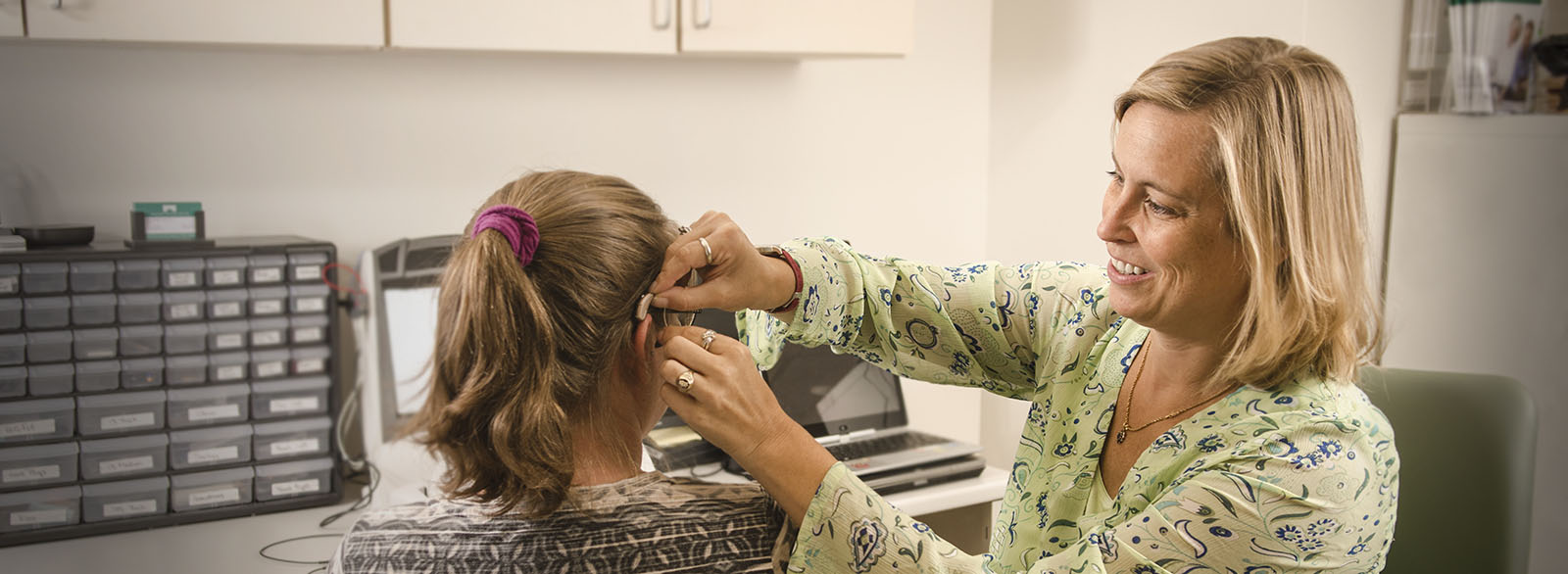 Audiologist Laura Burger fitting a patient with a hearing aid