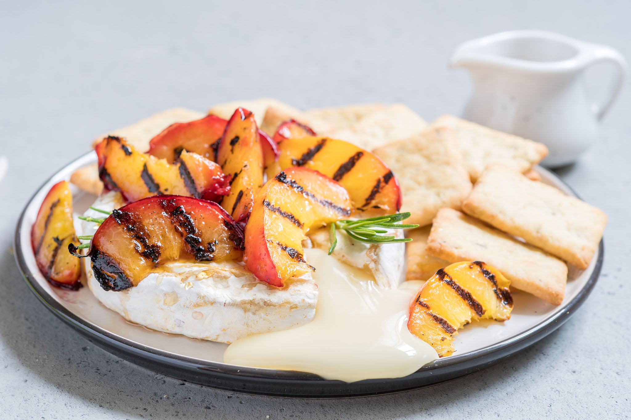 Grilled peached on a plate with brie cheese.