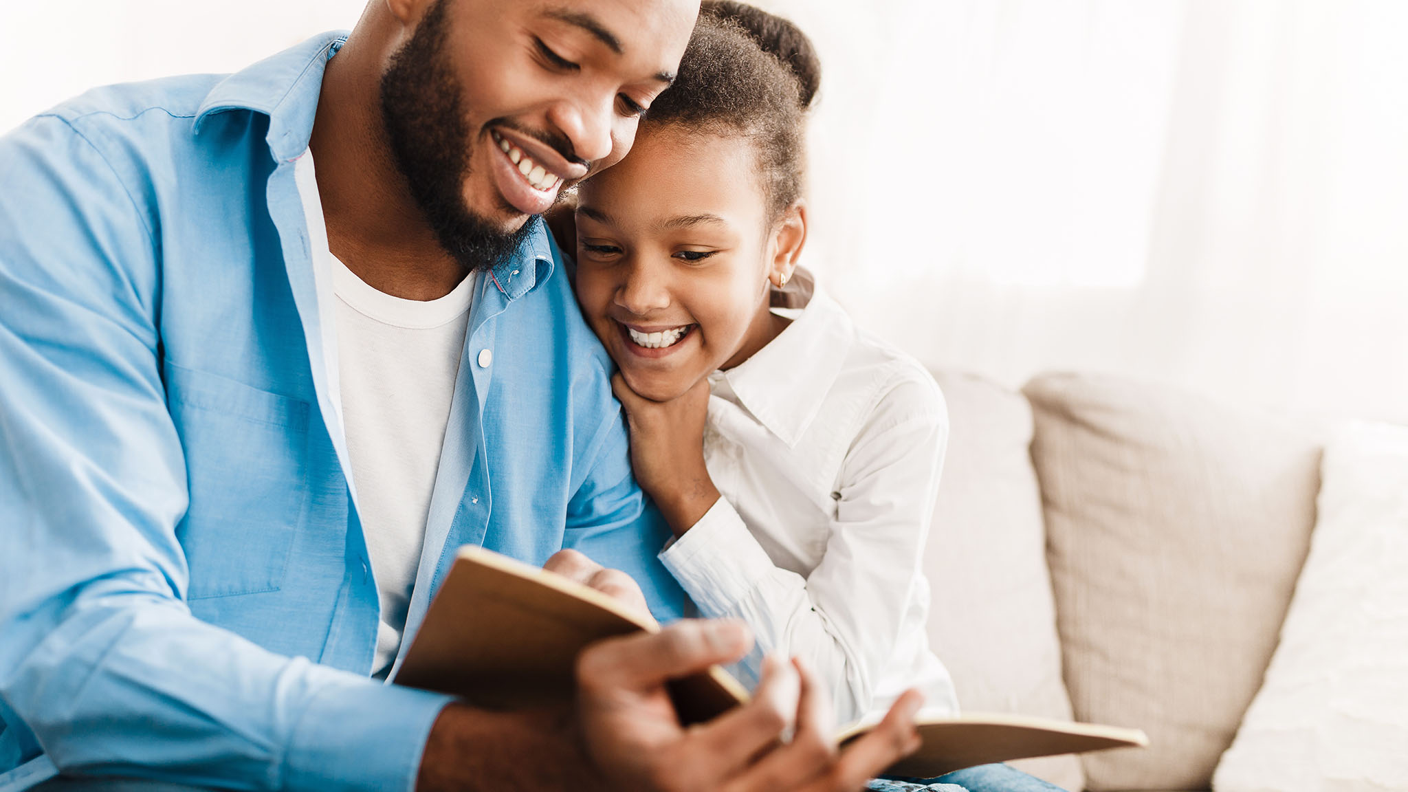 Man reading a book to his daughter.