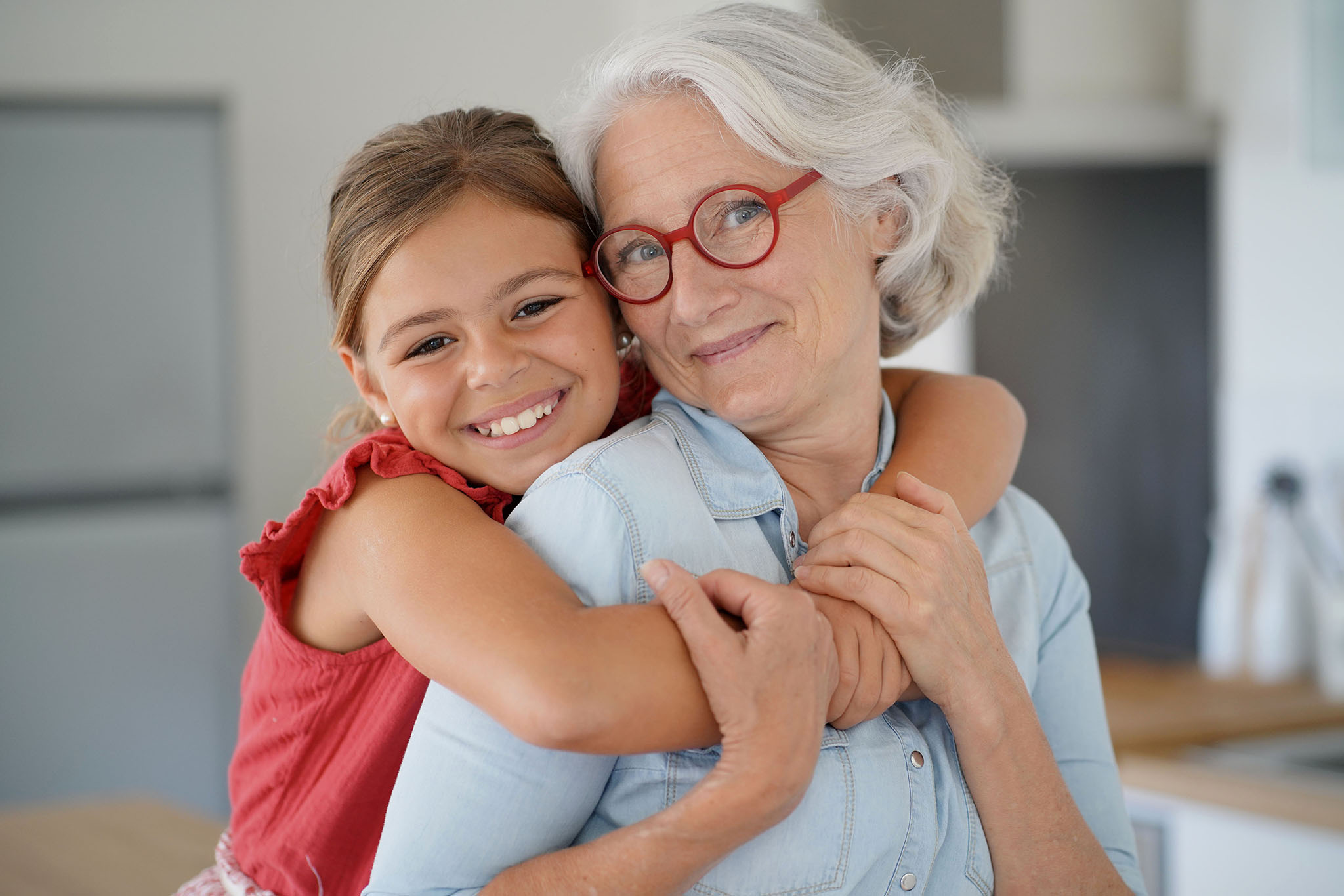 Older women with granddaughter's arms around her neck..