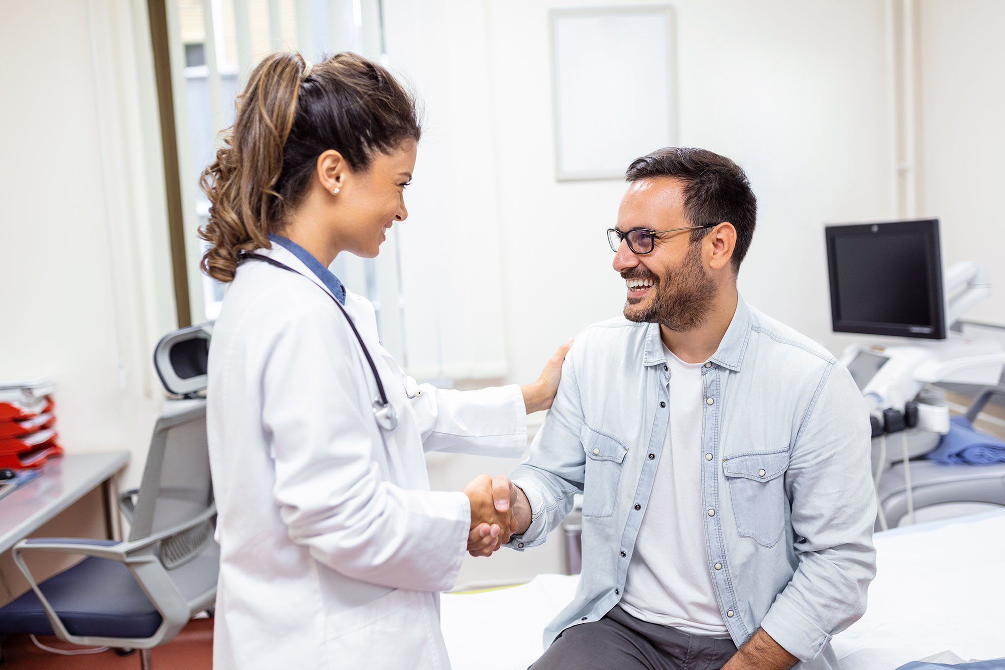 Female physician shaking male patient's hand.