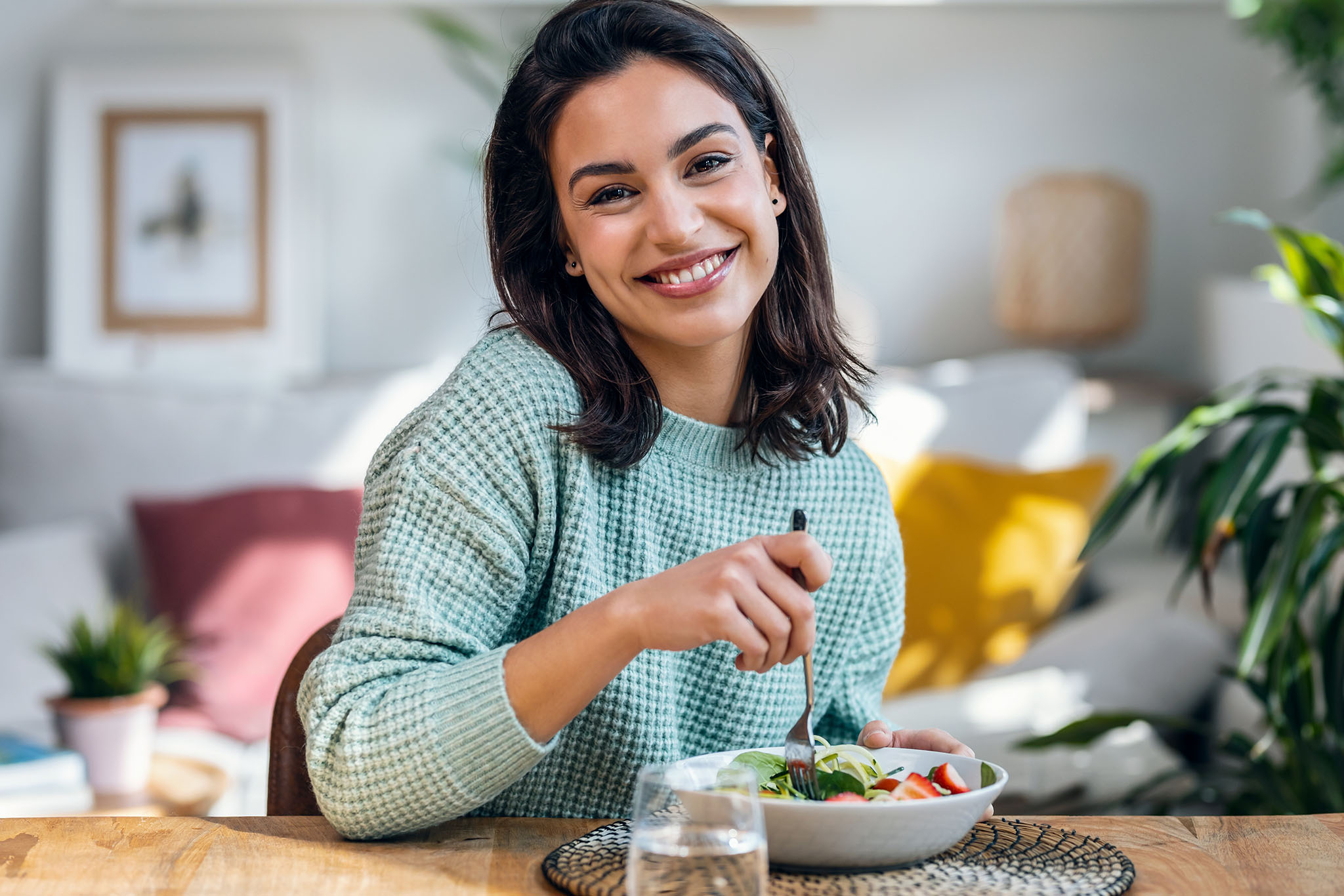 Young women smiling and eating a salad.