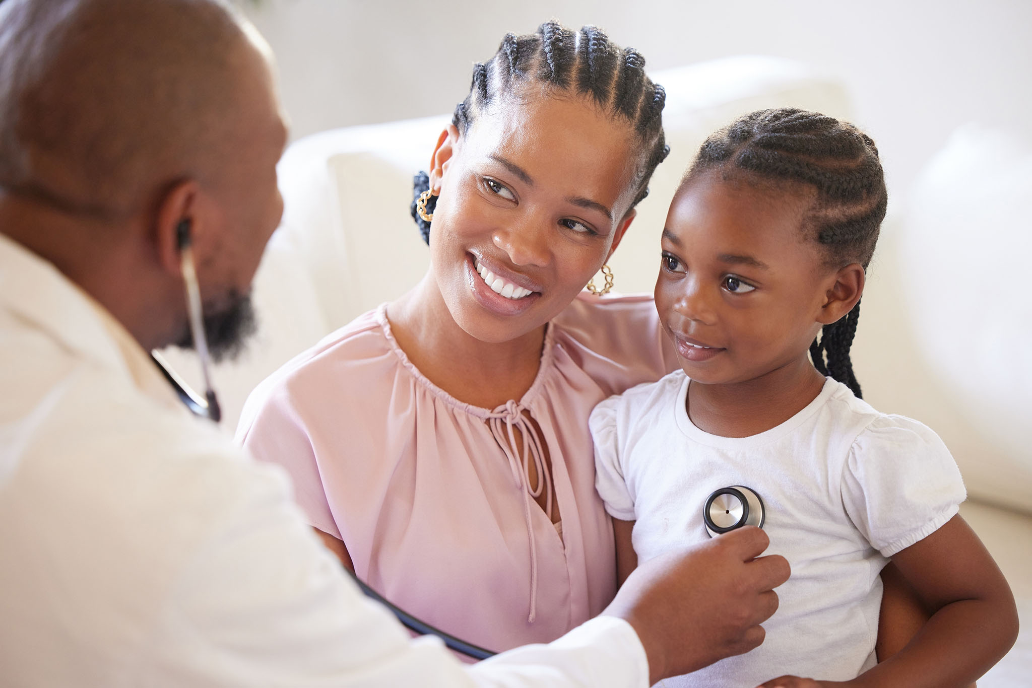Mother holding child. Doctor listening to child's heart.