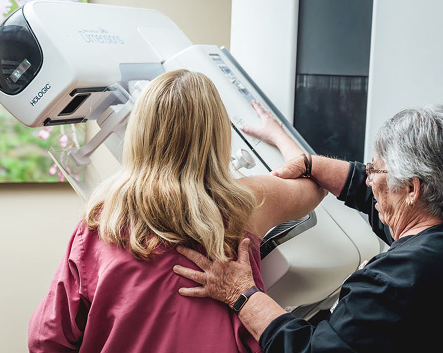 Technician performing a mammogram on a patient.