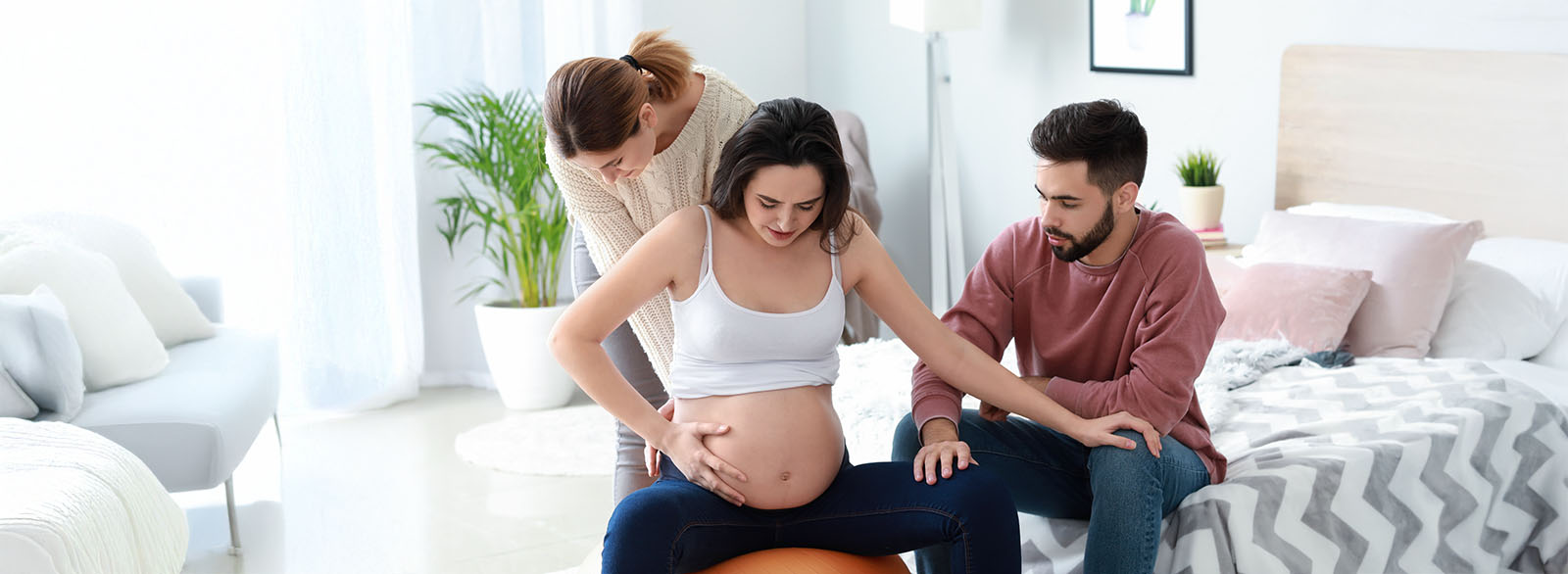 Doula assisting a pregrant woman during birth as her partner comforts her.