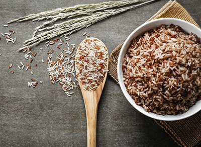 Wooden spoon next to bowl of rice