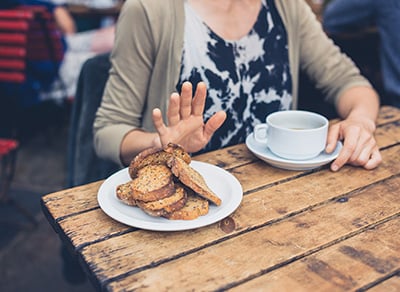 Woman holding up her hand to a plate of toast.