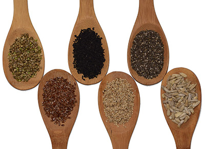 Arranged wooden spoons with various seeds in them.