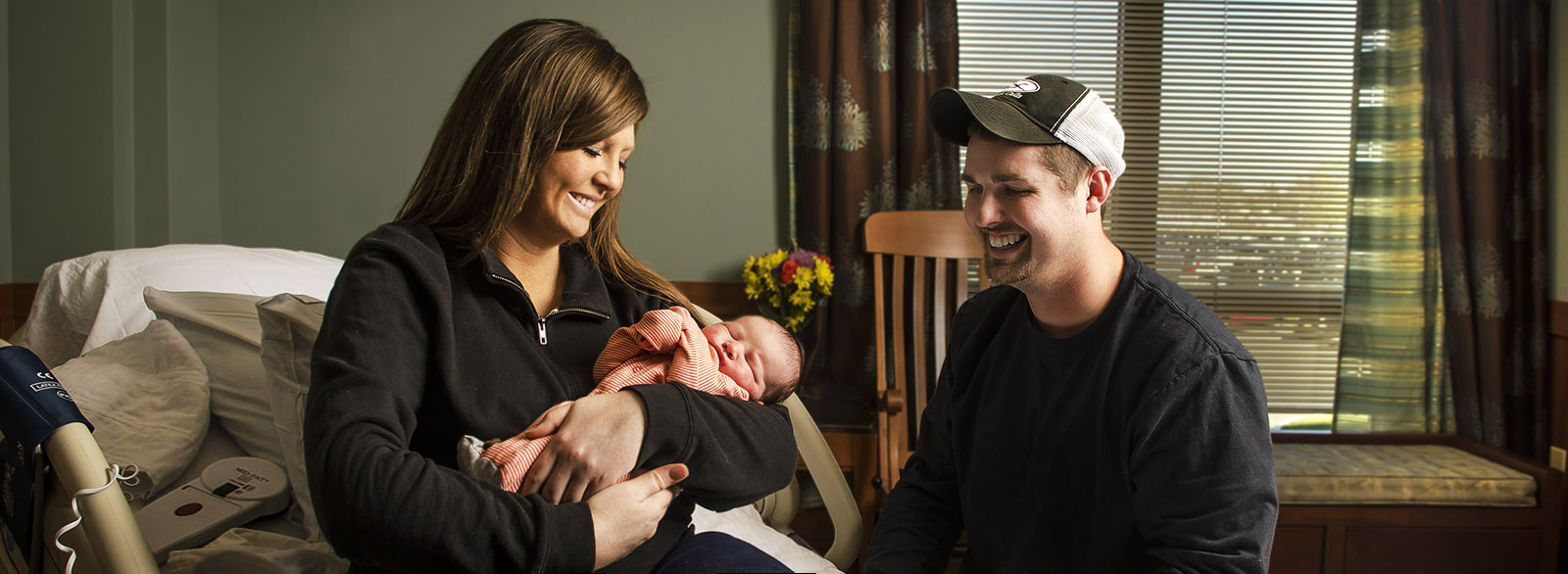 New mother holding her baby with husband nearby in the Birthing Center at Columbus Regional Health.