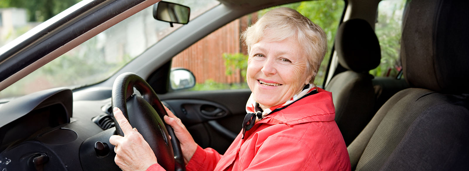 Woman in her 70s in the driver's seat of a car.