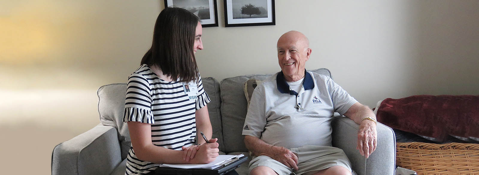 A palliative care social worker visits with an elderly patient at his home.