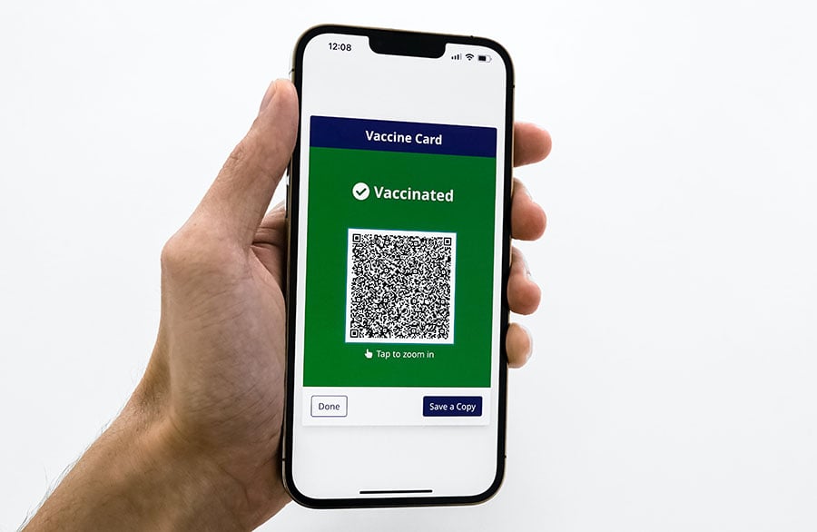 Hand holding smartphone showing Vaccine Card QR code
